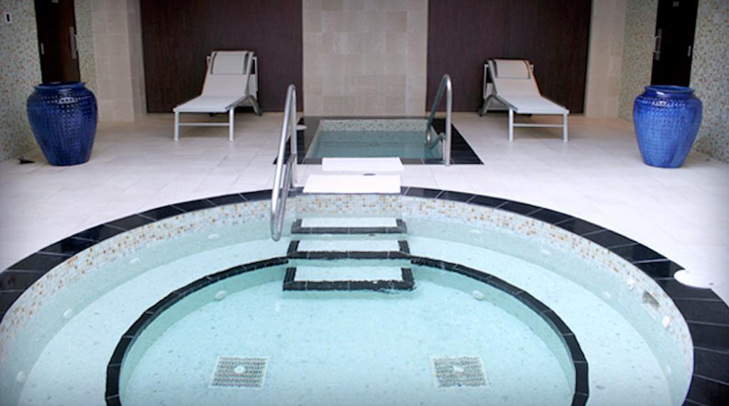 Hard Rock Hotel & Casino Biloxi Exterior photo The photo shows a spa area featuring a circular hot tub or jacuzzi, surrounded by a black stone border. There are steps leading into the water, and the interior of the tub appears to be tiled. In the background, there are two white lounge chairs posi